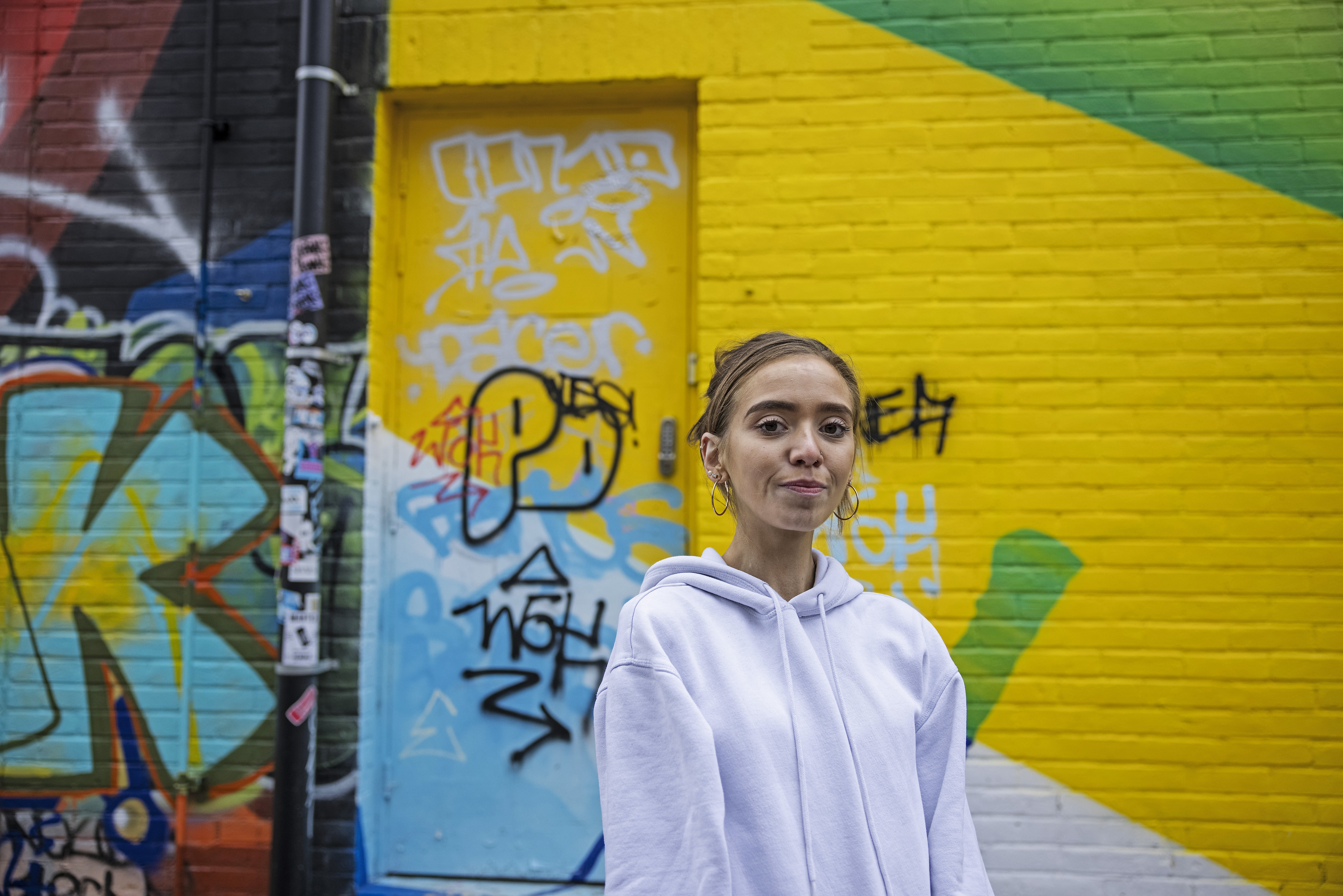 A student stands in front of a mural