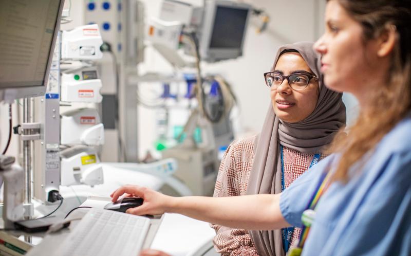 Two doctors are looking at a screen in a lab