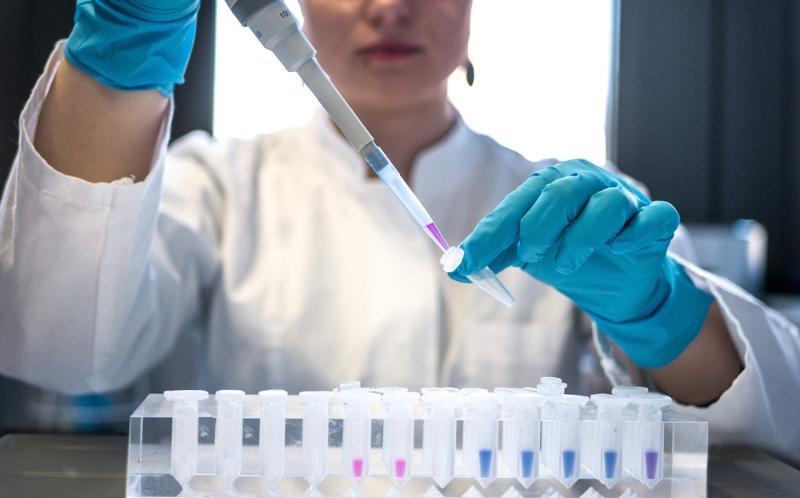 Female scientist pipetting coloured chemicals into a tube