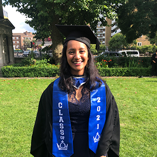 Girl standing in the sun in graduation gown and cap