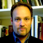 portrait of Angus Nicholls in front of bookshelves