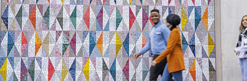 Students walking past a colourful background