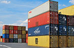 Lots of red, blue and yellow shipping containers arranged on a dock