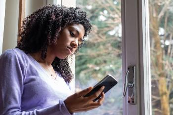 Young woman looking at her phone by a window