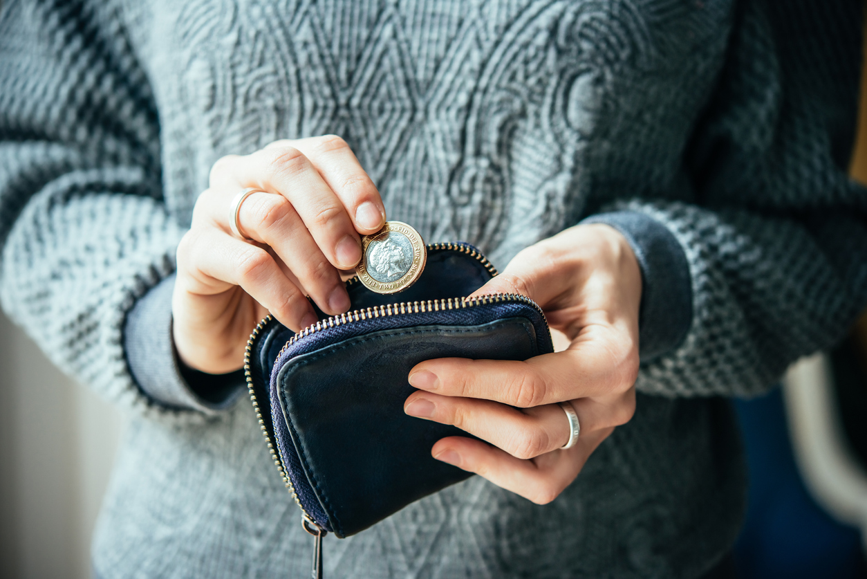 Person putting a two-pound coin into purse