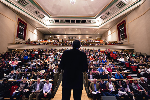 Lecturer looking out from stage to a full lecture theatre