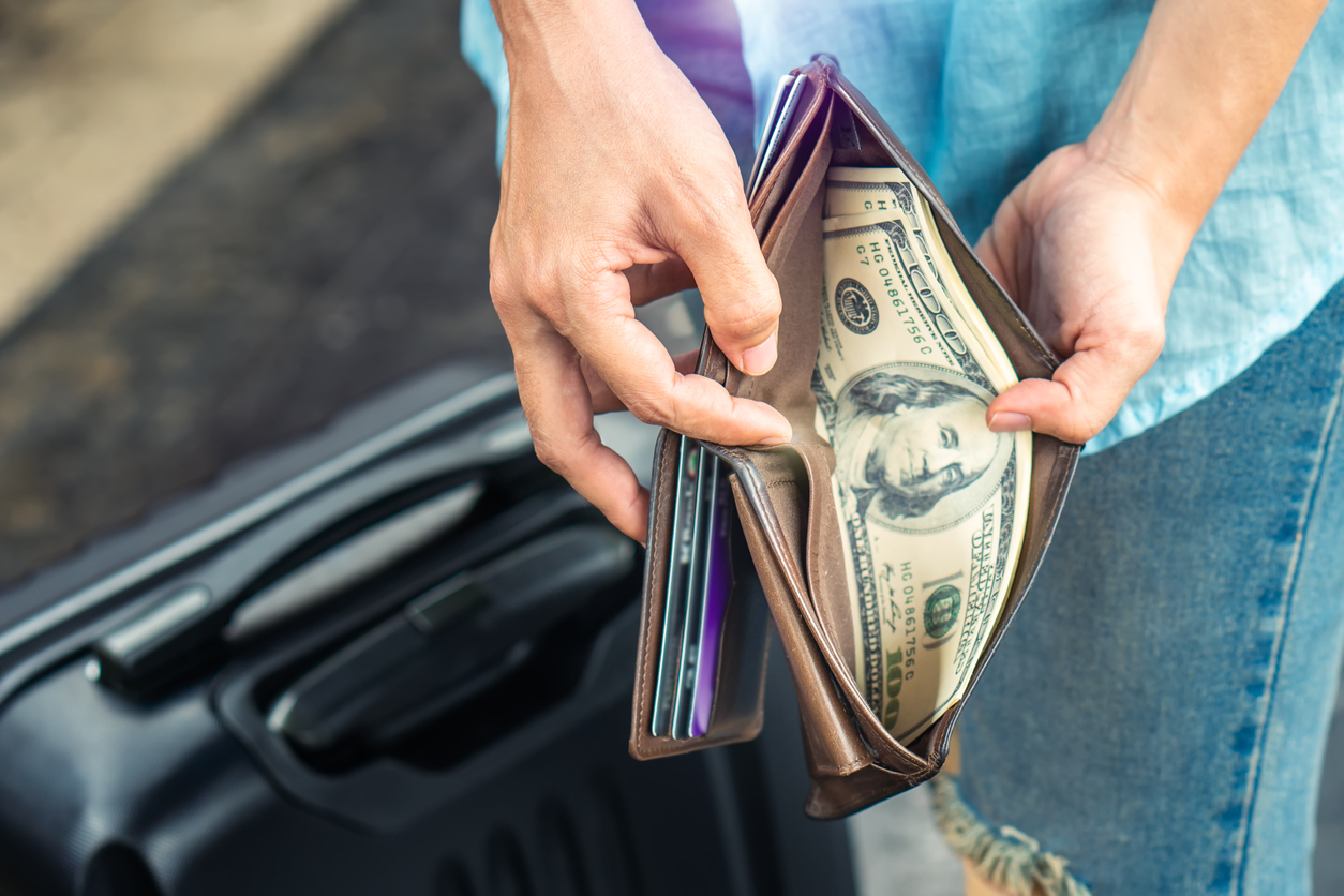 Person opening a wallet with bank notes inside