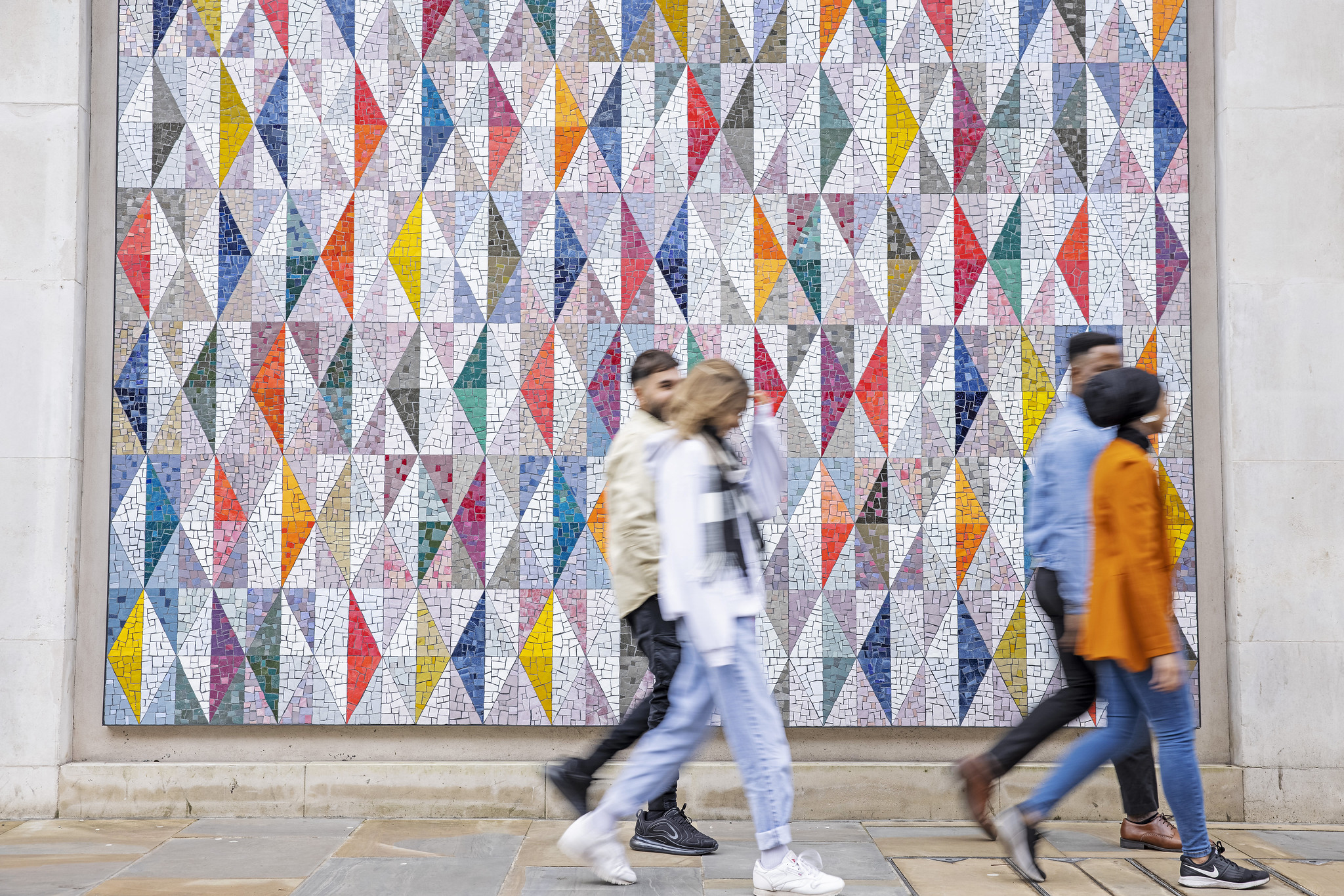 Students walking in front of a colourful background