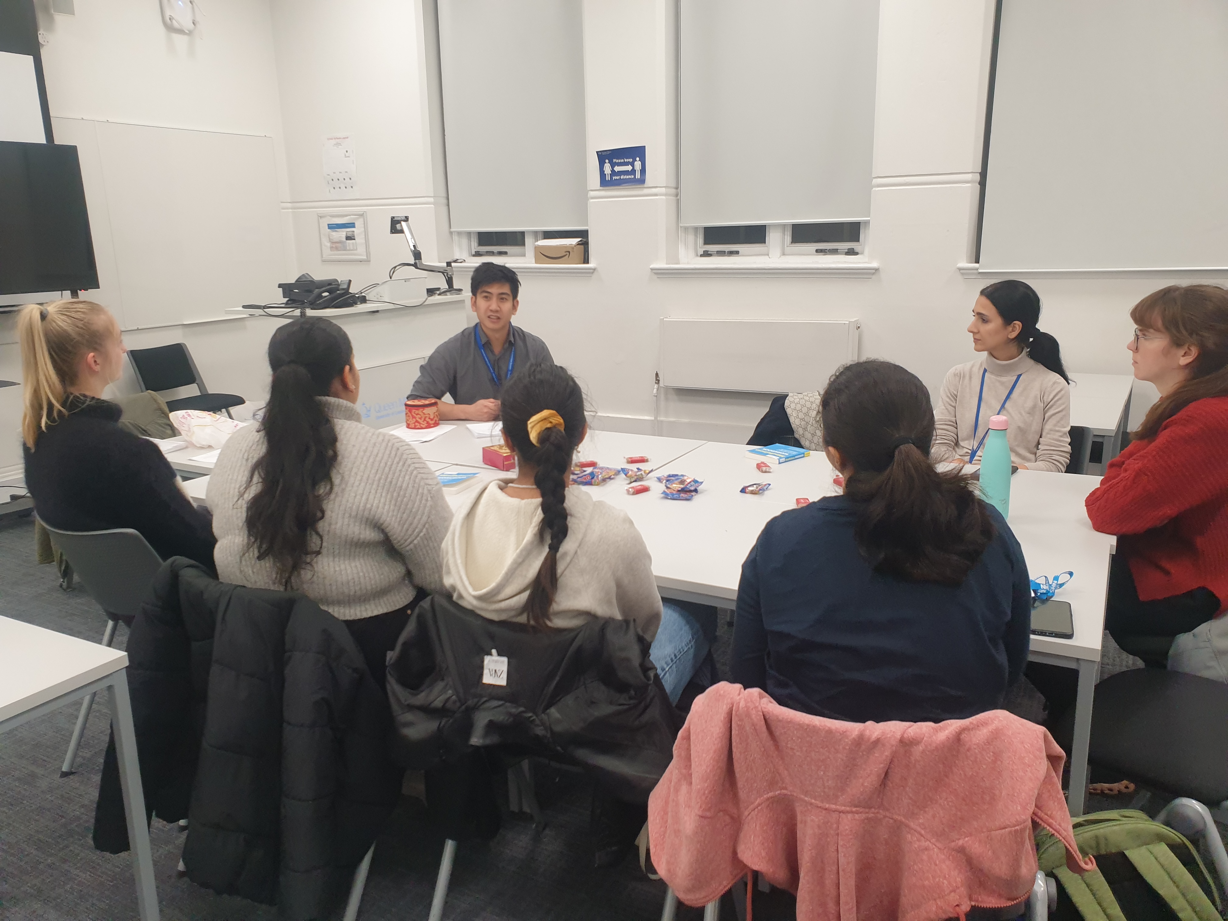 Students sitting around a table with a wellbeing adviser