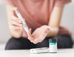 Woman using lancet on finger for checking blood sugar level.