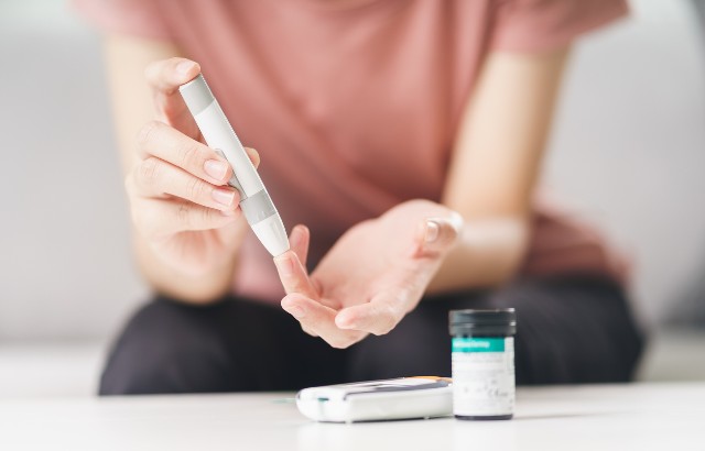 Woman using lancet on finger for checking blood sugar level.